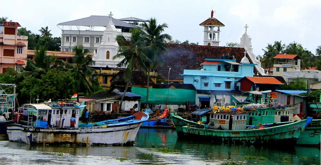 Fishing boats moored in front of churches and houses on the waterfront at Fort Kochi, Kerala