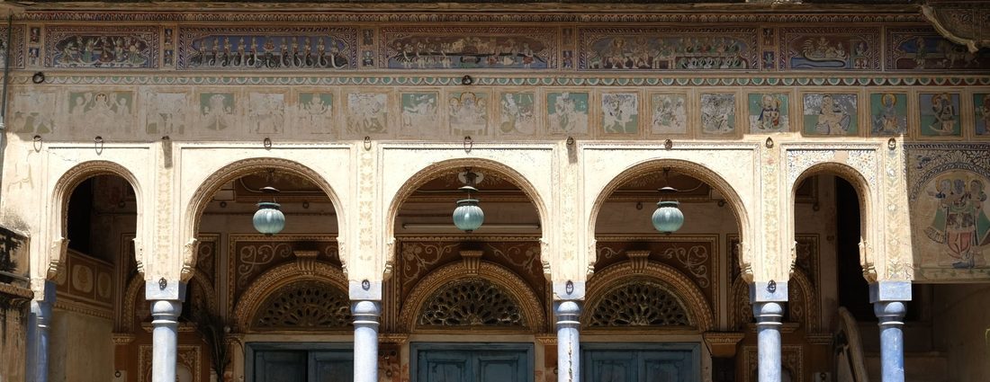 Painted frescoes above the arcaded facade of a Shekhawati haveli in Mandawa, Rajasthan